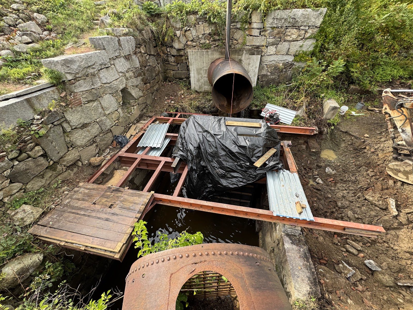 The penstock adapter staged beside the old stonework.
